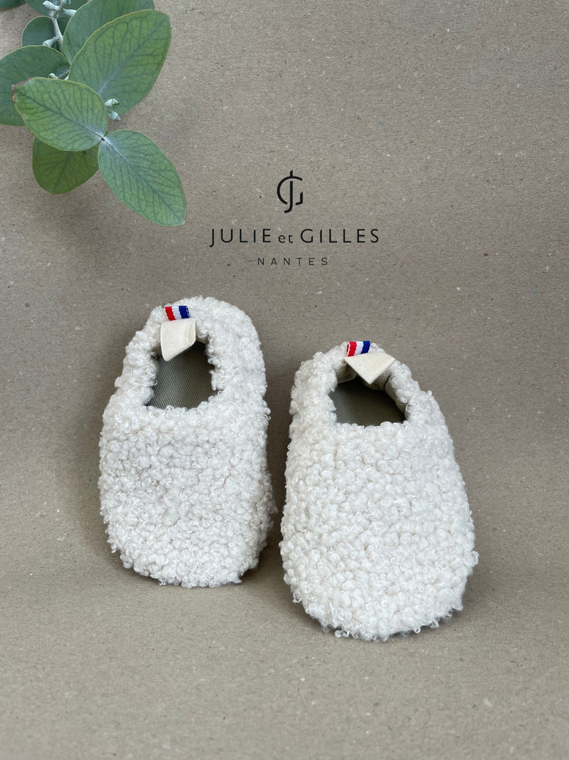 Chaussons en tissu souple pour bébé et enfant, fabriqués en France avec des matières de qualité. Conçus en tissu bouclé crème tout doux, ces chaussons offrent confort, légèreté et souplesse aux petits pieds. Leur semelle en croûte de cuir antidérapante assure une bonne accroche pour les premiers pas. Idéal pour les tout-petits, dès la naissance. Fabrication artisanale française, finitions soignées et style intemporel.